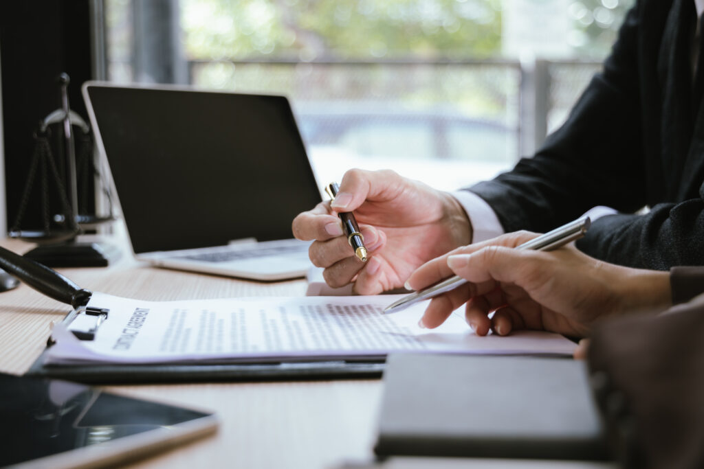 Close up of male lawyer working with contract documents and wooden hammer on table in courtroom. Justice and law. Judge in suit or lawyer working with documents. Law. Close up.